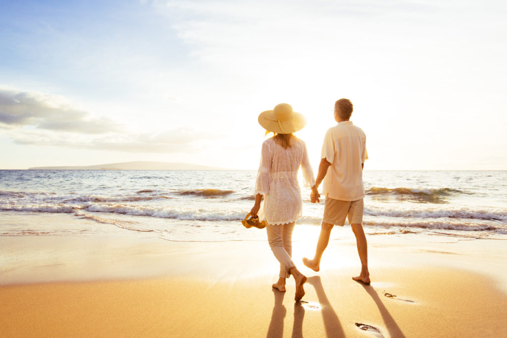 Mature Couple Walking on the Beach at Sunset as they have secured their inheritance tax