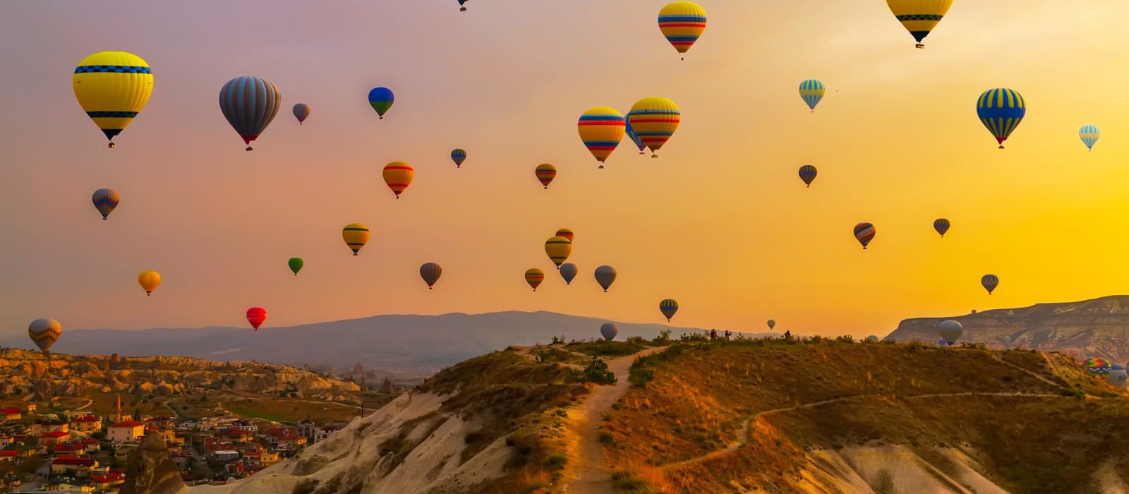 Lots of hot air balloons over a hillside