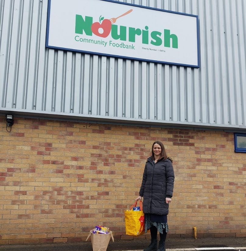 a woman standing outside the 'Nourish' foodbank.